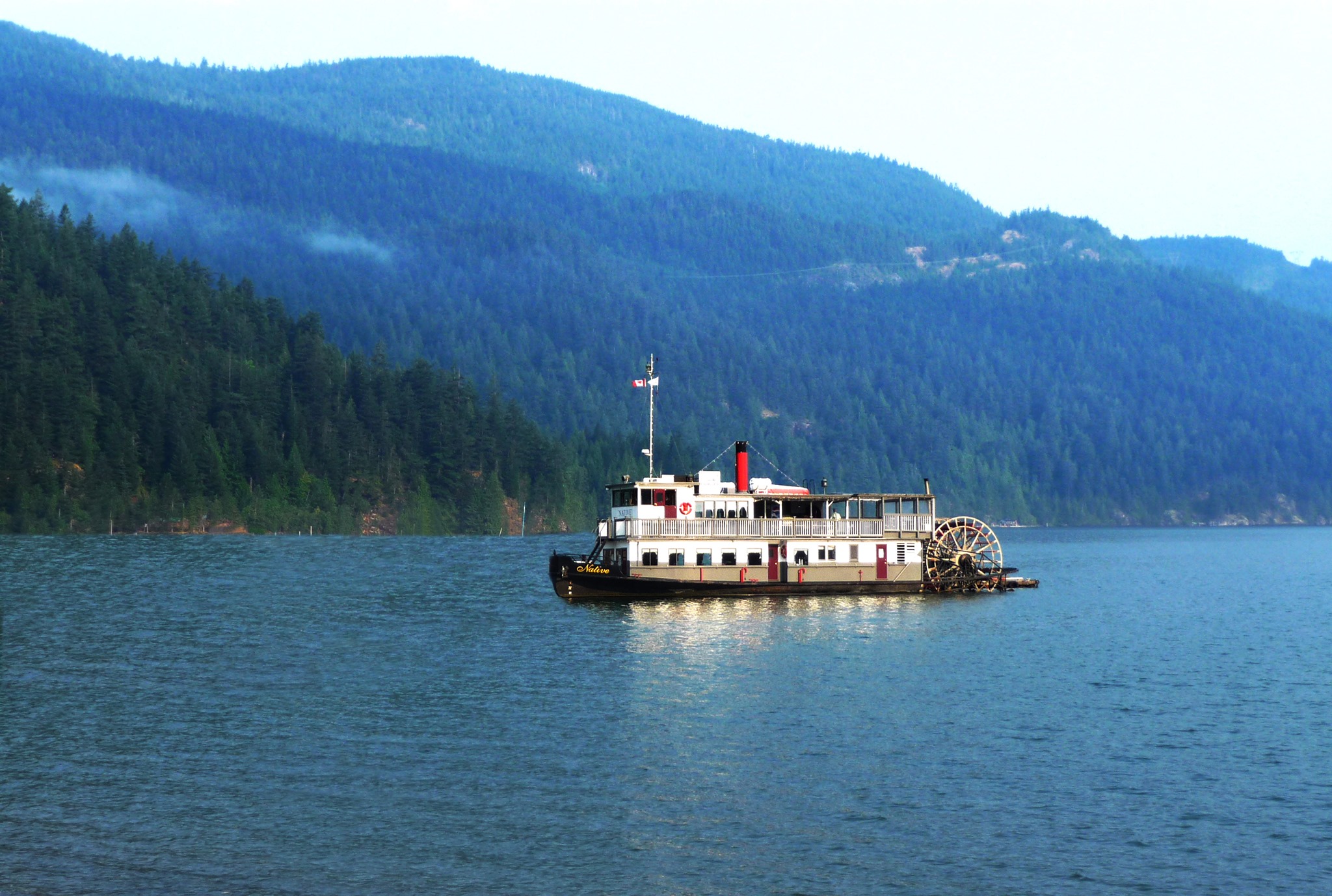 MV Native cruising with a scenic mountain lake backdrop